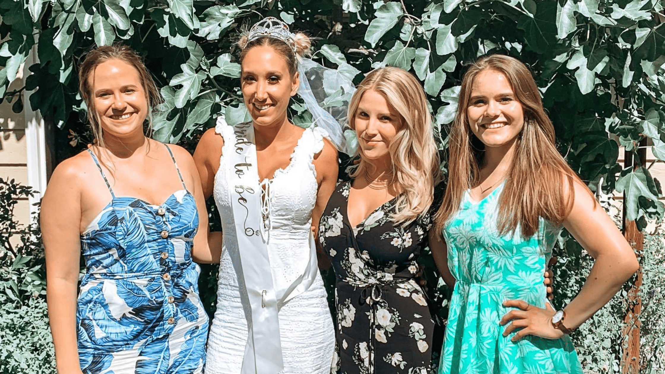 Four people posing for a photo. One person is wearing a 'bride-to-be' sash.