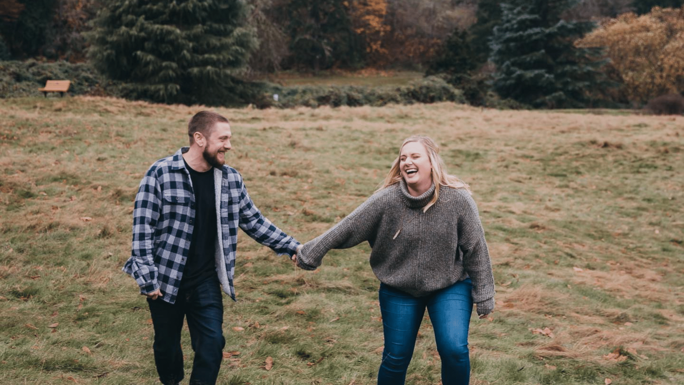 Couple laughing and holding hands in a field in Bothell, WA